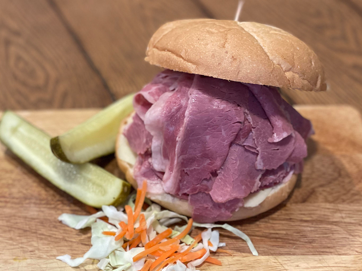 a sandwich on a cutting board with a pickle and cheese